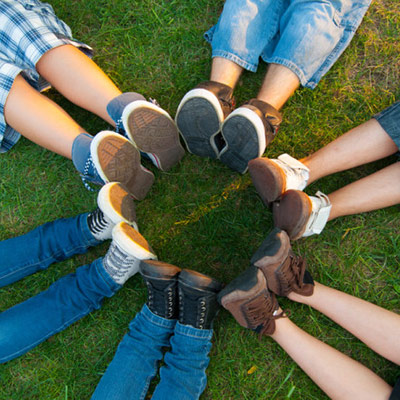 Teens lying down in a circle with feet touching